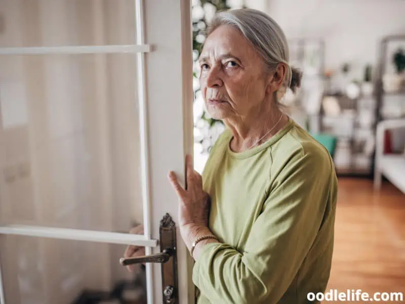 old woman stands by the door